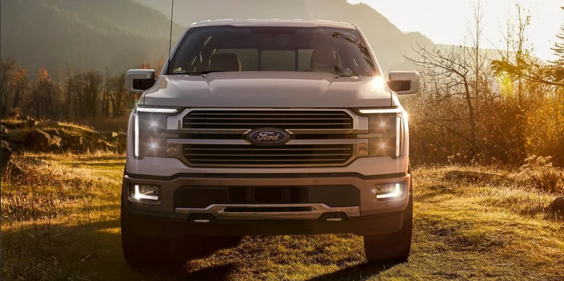 A white 2024 Ford F-150 off-roading through a field.