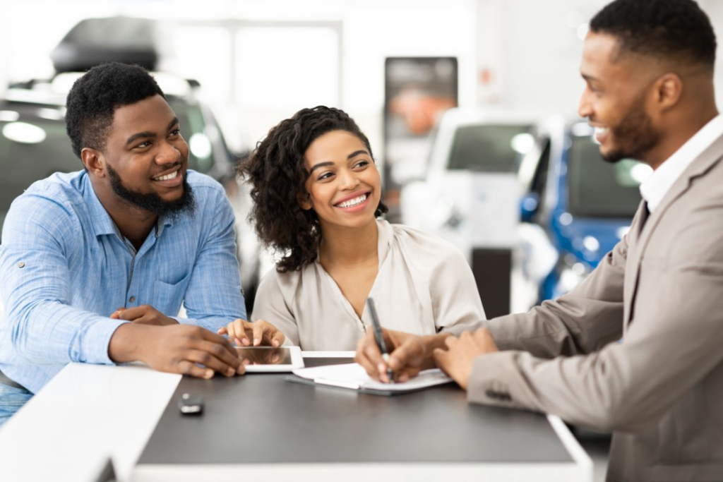 A couple discussing a car sale with a car salesmen.