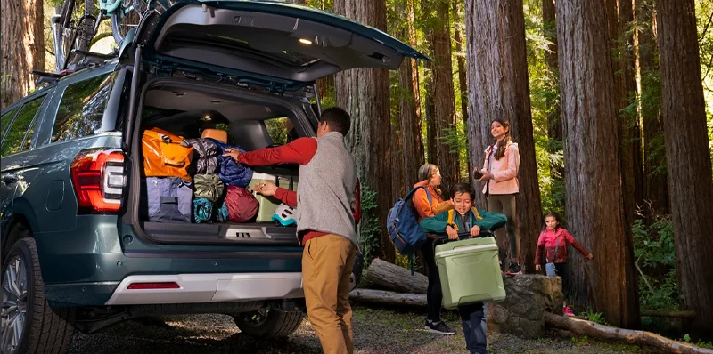 A family loading camping gear in to the back of a 2025 Ford Expedition.