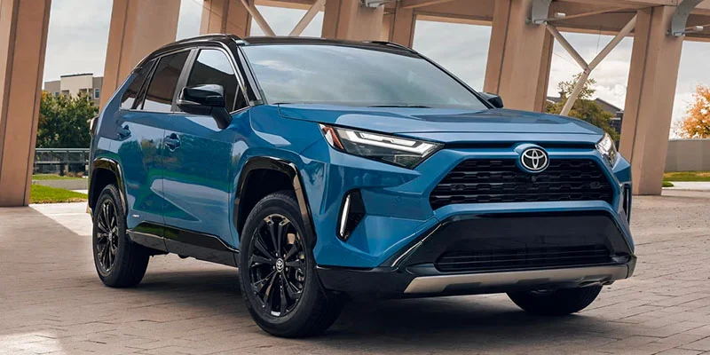 A blue 2025 Toyota RAV4 Plug-in Hybrid parked with grass in the background.