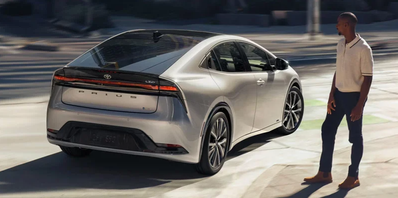 A silver 2025 Toyota Prius driving down the road.