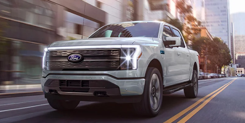 A grey 2025 Ford F-150 Lightning driving down the road.