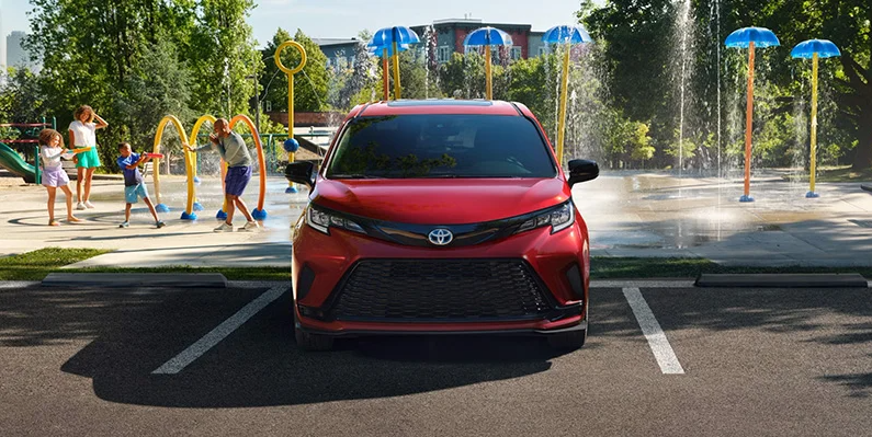 A red 2025 Toyota Sienna parked in front of a playground.