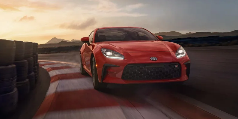 A red 2025 Toyota GR86 rounding the corner on a racetrack.