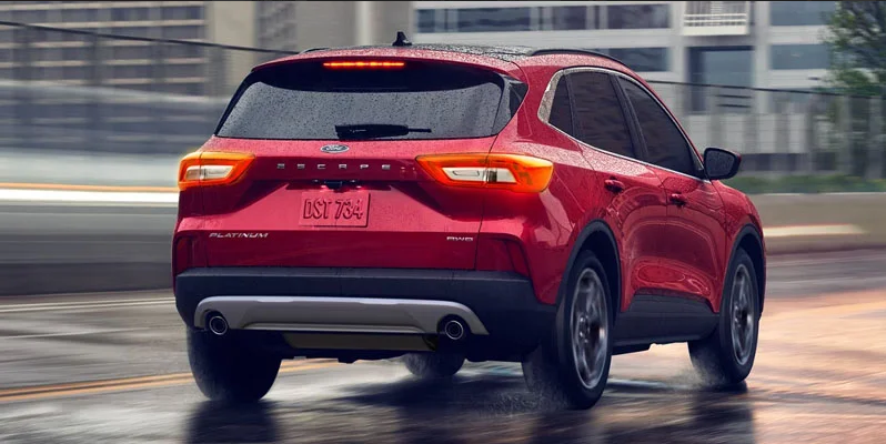 A red 2026 Ford Escape driving down a rainy road.