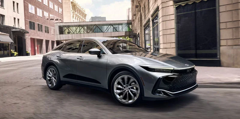 A silver 2026 Toyota Crown making a turn down a city street.