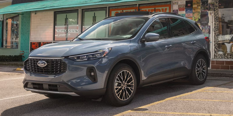 A blue 2026 Ford Escape is parked on the street near a vibrant, colorful storefront, highlighting its sleek SUV design.