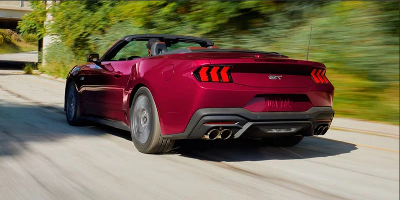 A red 2026 Ford Mustang driving down the road.